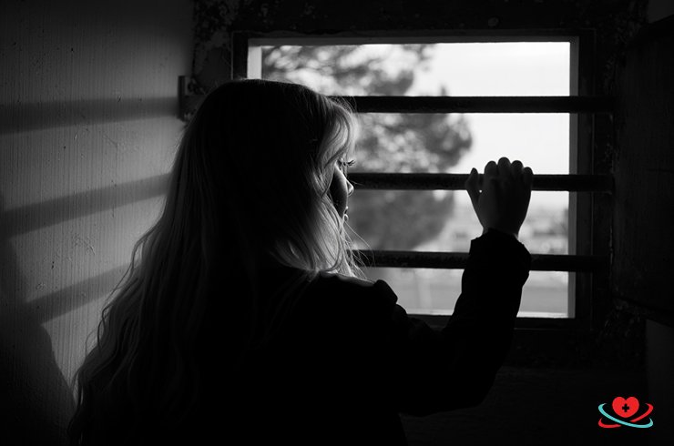 Девушка одиноко стоит у окна